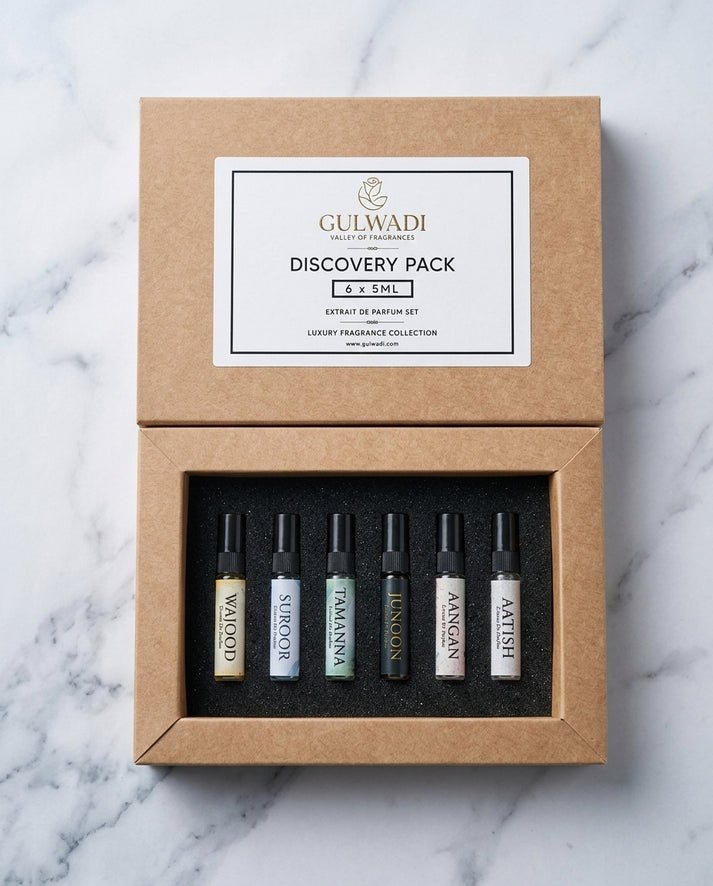 An open kraft gift box containing a Gulwadi Discovery Pack with six 5ML extrait de parfum tester vials on a marble surface