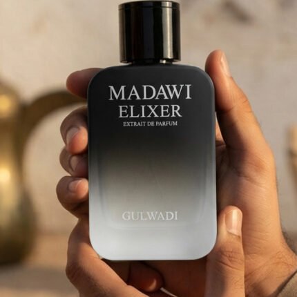 Hands holding a black and silver ombre glass bottle of Madawi Elixer Extrait de Parfum by Gulwadi