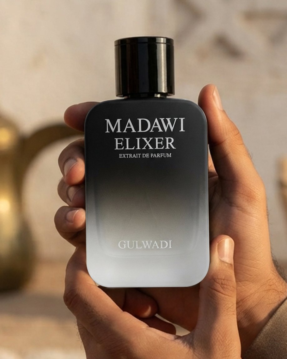 Hands holding a black and silver ombre glass bottle of Madawi Elixer Extrait de Parfum by Gulwadi