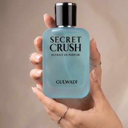 Hands holding a soft blue frosted glass bottle of Secret Crush Extrait de Parfum by Gulwadi