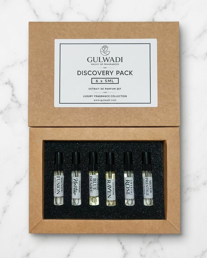 An open kraft gift box containing a Gulwadi Discovery Pack with six 5ML extrait de parfum tester vials on a marble surface