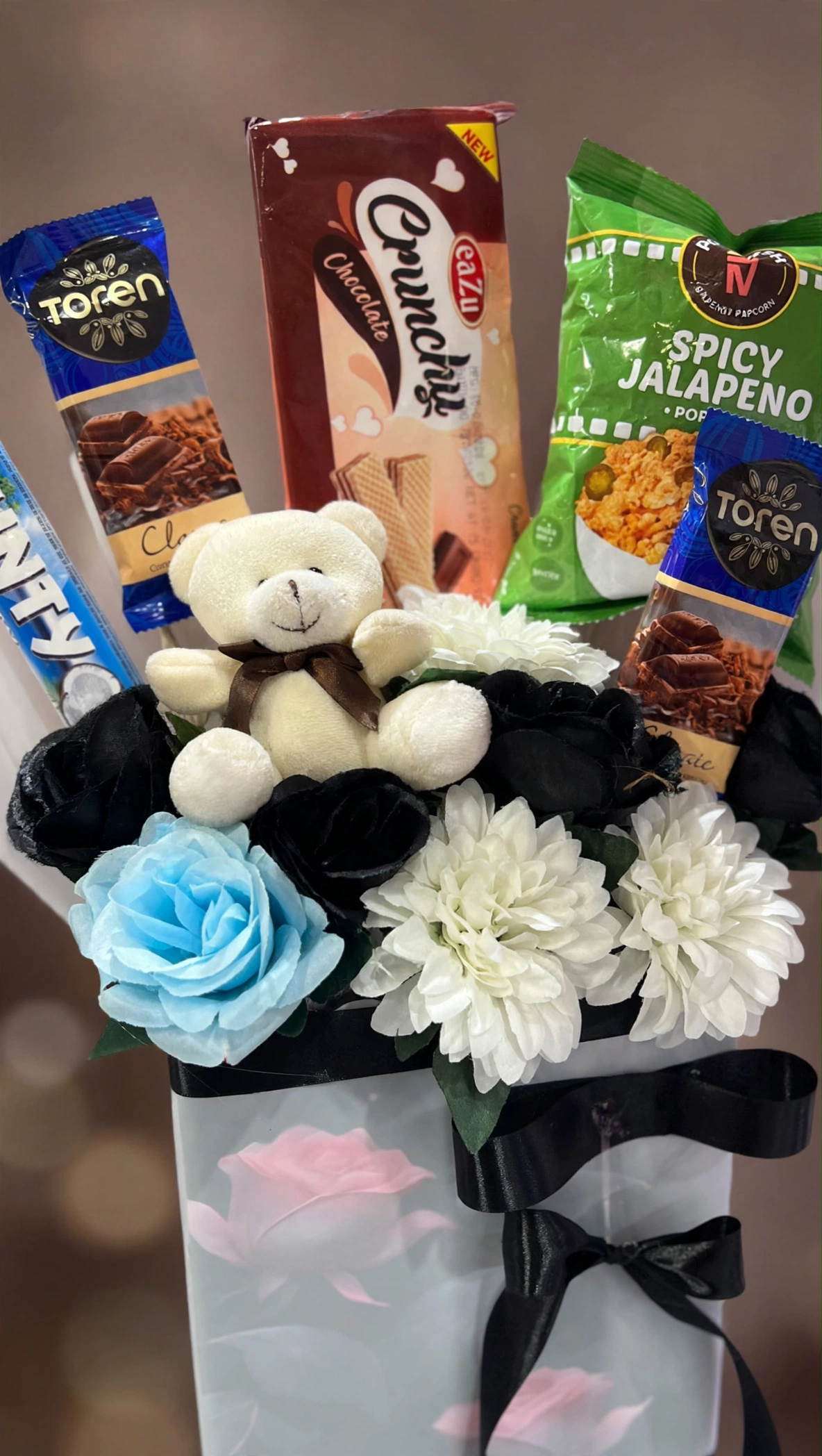 Close-up of teddy, roses and chocolates in the snack gift bag
