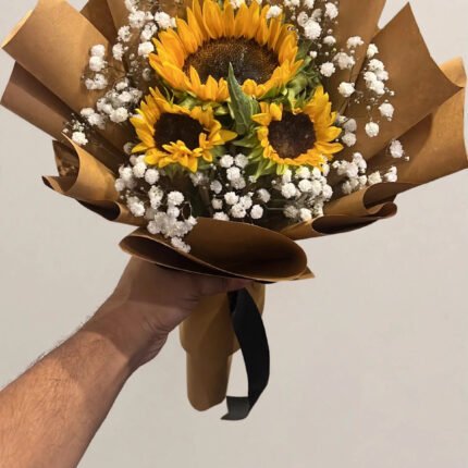 Fresh sunflower bouquet with white baby's breath wrapped in brown kraft paper